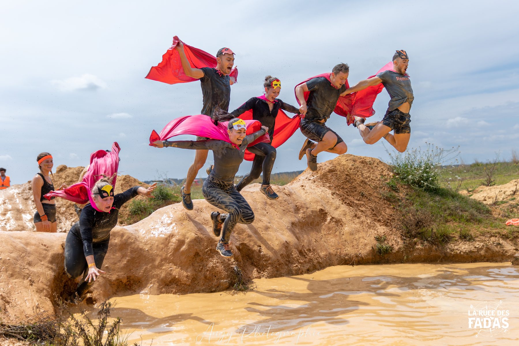 Participants déguisés sautant dans un bassin de boue